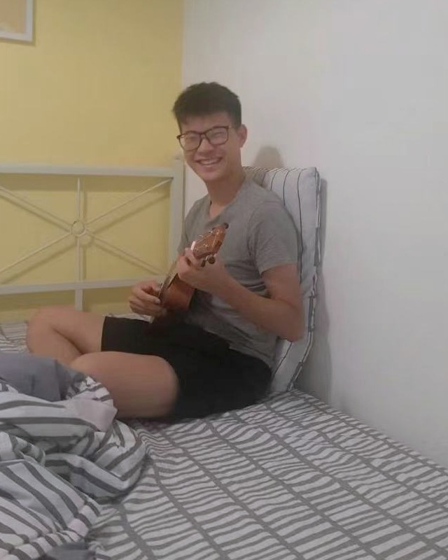 Jackie playing a small string instrument and smiling at the camera